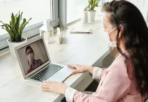 Two people speaking on video chat with masks on