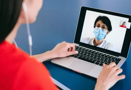 Person talking on a video call with a healthcare worker in a mask.