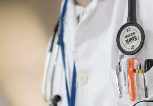 close-up of a doctor's chest with a stethoscope and a pocket full of pens